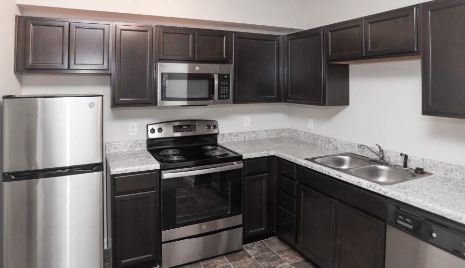 a kitchen with stainless steel appliances and black cabinets at The Alpine Studios