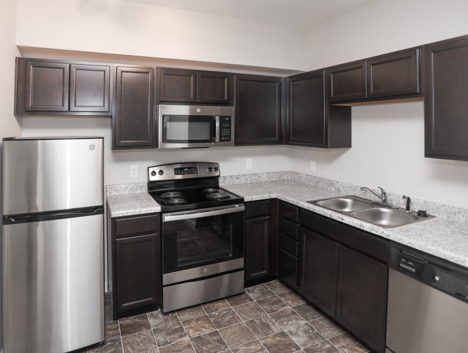 a kitchen with stainless steel appliances and black cabinets at The Alpine Studios