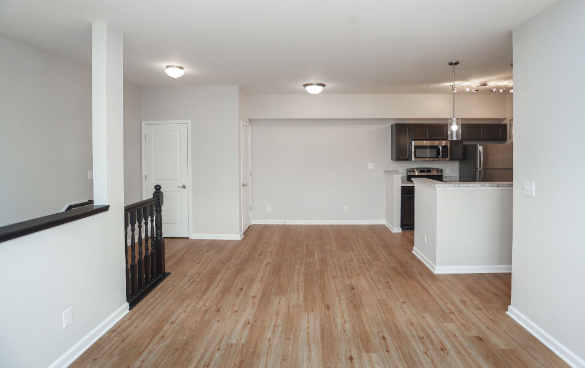 an empty living room with hardwood floors and a white kitchen at The Alpine Studios
